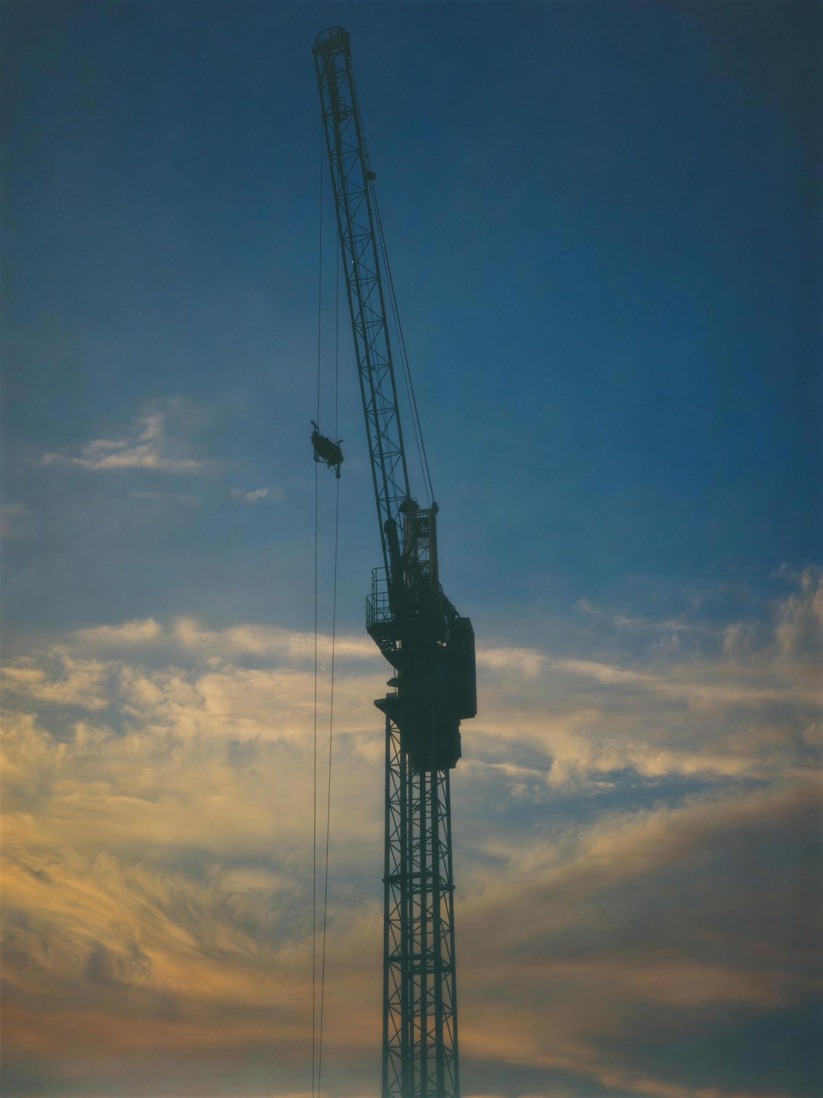 Grue de chantier en silhouette sur un ciel d'heure dorée
